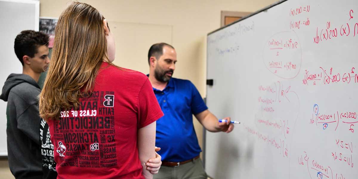 Math professor Dr. Hein teaching a student calculus on a whiteboard