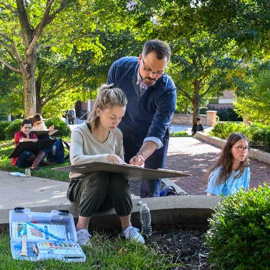 John Haigh assists a student in an outdoors Architecture class