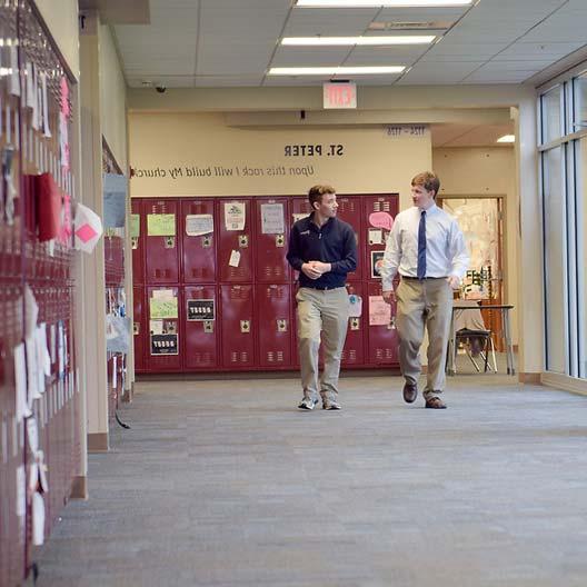 Two men walking along a school hallway