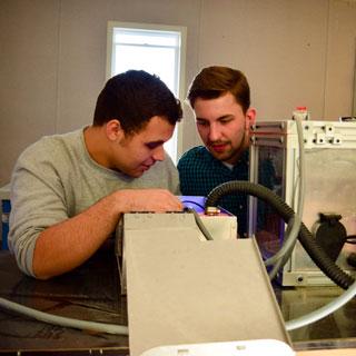 Two students working with a machine