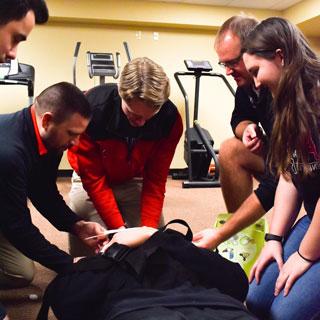 Health, Wellness, and Exercise Science Students practice emergency care, with a fellow student posing on a stretcher