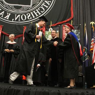 Graduate shaking hands with faculty at Graduation