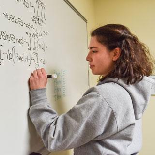 Student writing equations on the board