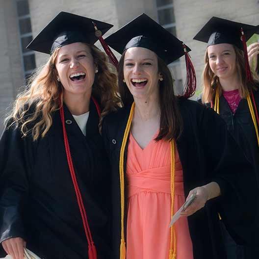 Two graduates laughing in their cap and gowns