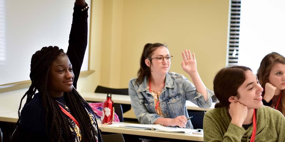 A BCYC Immersion participants raise their hands in class