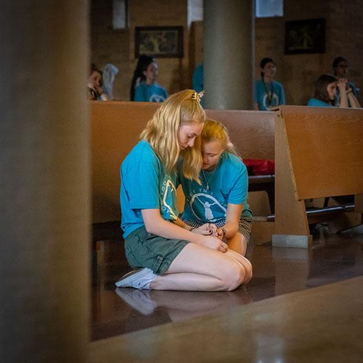 Two BCYC students comforting each other while praying in the abbey's guadalupe chapel 